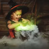 Mała czarownica w kapeluszu miesza w kociołku, tworząc zielony dym. To jak zrobic dym na Halloween!