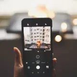 Telefon uchwycił urokliwy kadr: kubek z napojem, ozdobiony gwiazdkami, na tle miejskiego krajobrazu. To doskonała fotografia produktowa.