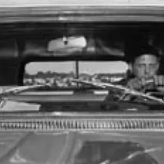 Lee Friedlander za kierownicą, patrzący przed siebie. Widok z wnętrza samochodu.