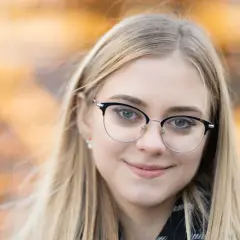 Uśmiechnięta blondynka w okularach, z rozmyciem tła. Idealna ogniskowa do portretu, by podkreślić oczy.