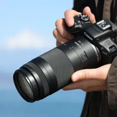 Dłoń trzyma aparat Canon z obiektywem 75-300, idealnym do fotografii przyrodniczej i sportowej, pozwalającym uchwycić odległe detale.
