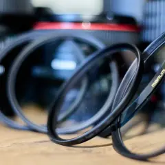 Kilka filtrów ochronnych na obiektyw leży przed aparatami.