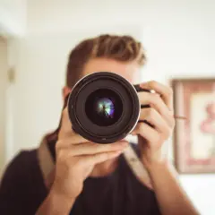 Mężczyzna z aparatem, który może być konkurentem Nikona, robi sobie selfie.