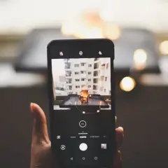 Telefon uchwycił urokliwy kadr: kubek z napojem, ozdobiony gwiazdkami, na tle miejskiego krajobrazu. To doskonała fotografia produktowa.