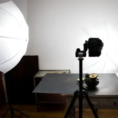 Przygotowania do sesji zdjęciowej jedzenia: awokado na stole, aparat na statywie i dwa softboxy.