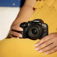 Dłonie trzymają aparat Canon EOS R10, gotowy do testów.