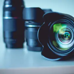Kilka obiektywów, w tym jeden z osłoną przeciwsłoneczną, leżących na stole. Idealny zestaw, jeśli zastanawiasz się, jaki obiektyw do krajobrazu wybrać.