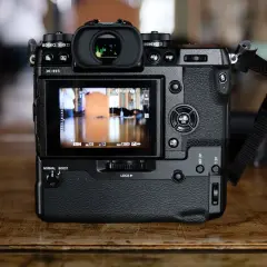 Tył aparatu Fujifilm X-H1 z widocznym ekranem LCD, przyciskami sterującymi i paskiem na nadgarstek.