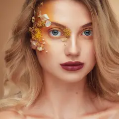Fotografia beauty: kobieta z niebieskimi oczami i artystycznym makijażem z elementami natury.