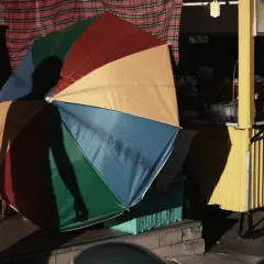Kolorowy parasol rzuca cień na uliczny stragan z mango sticky rice. Fotografia miejska.