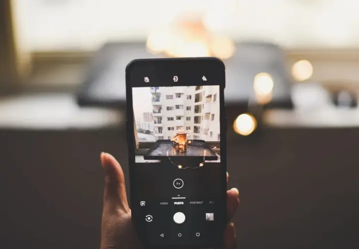 Telefon uchwycił urokliwy kadr: kubek z napojem, ozdobiony gwiazdkami, na tle miejskiego krajobrazu. To doskonała fotografia produktowa.