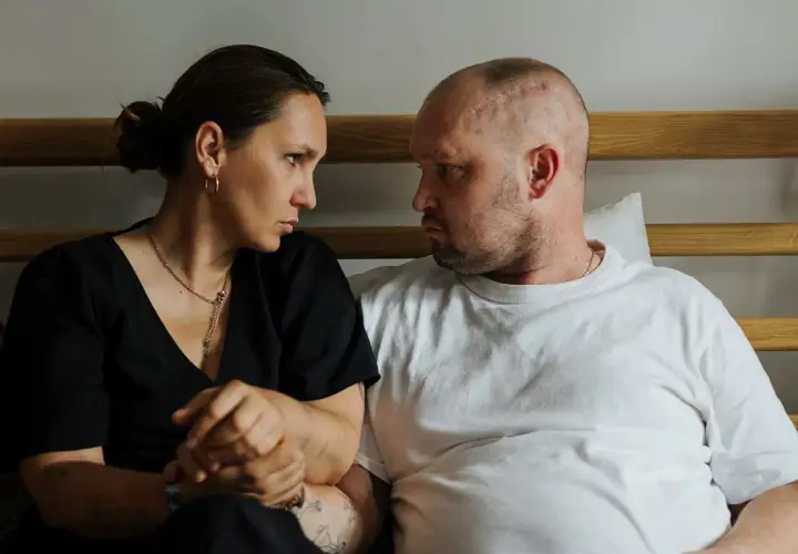 Anna Hernik i jej partner patrzą na siebie z powagą, siedząc obok siebie.