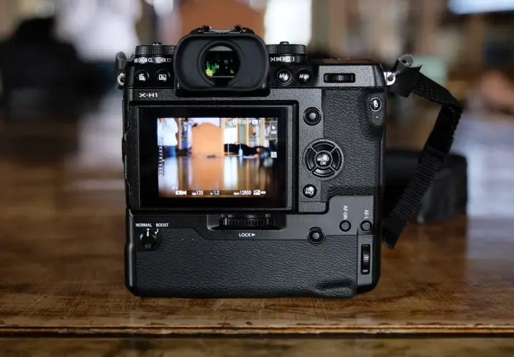 Tył aparatu Fujifilm X-H1 z widocznym ekranem LCD, przyciskami sterującymi i paskiem na nadgarstek.