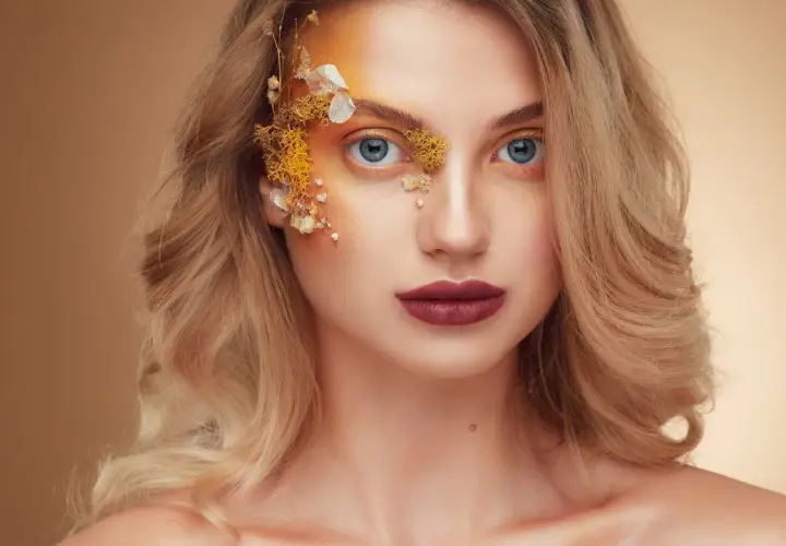 Fotografia beauty: kobieta z niebieskimi oczami i artystycznym makijażem z elementami natury.