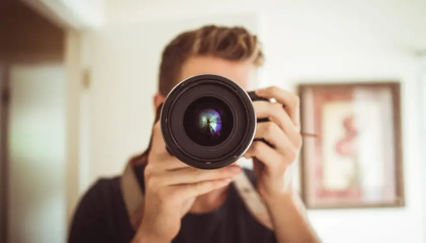 Mężczyzna z aparatem, który może być konkurentem Nikona, robi sobie selfie.