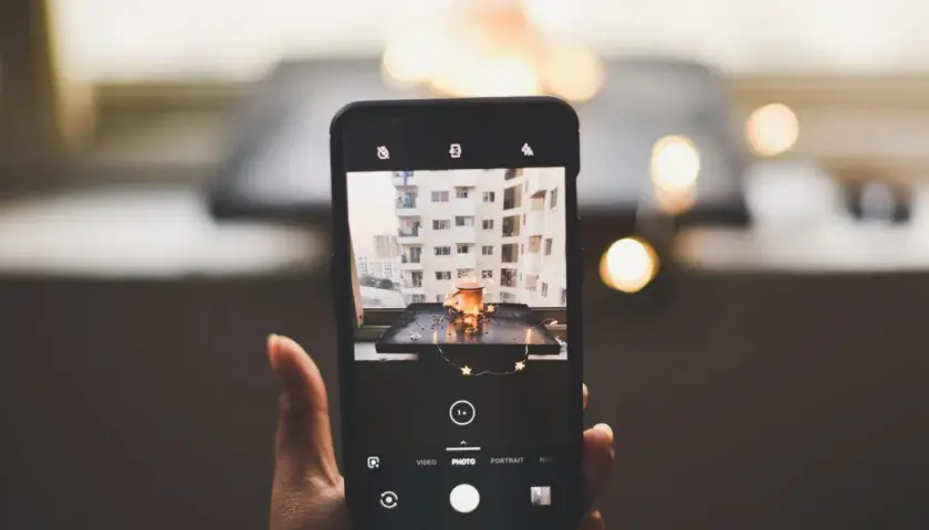 Telefon uchwycił urokliwy kadr: kubek z napojem, ozdobiony gwiazdkami, na tle miejskiego krajobrazu. To doskonała fotografia produktowa.