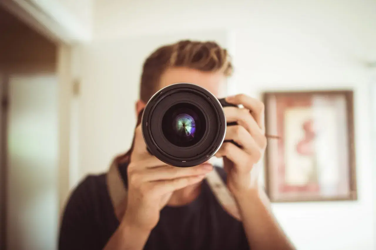 Mężczyzna z aparatem, który może być konkurentem Nikona, robi sobie selfie.