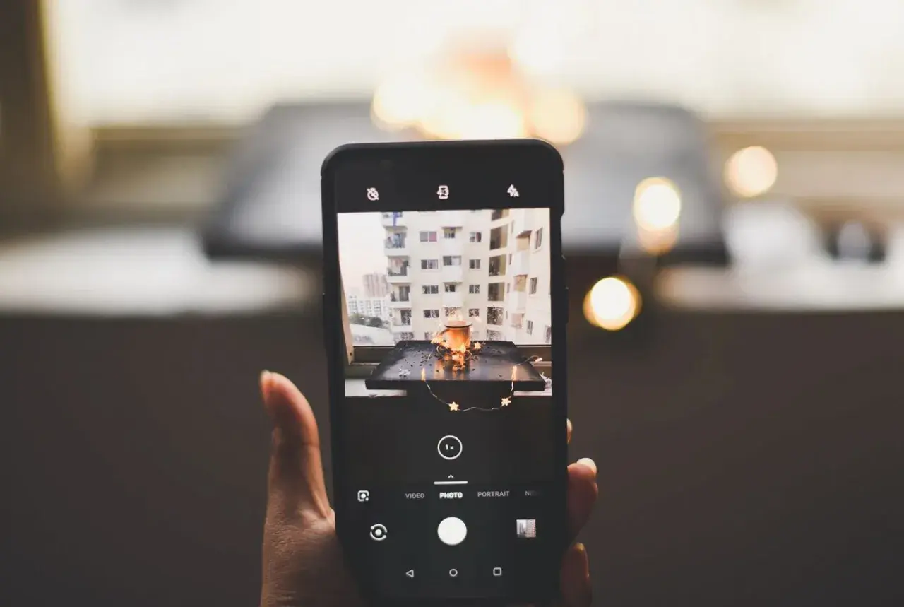 Telefon uchwycił urokliwy kadr: kubek z napojem, ozdobiony gwiazdkami, na tle miejskiego krajobrazu. To doskonała fotografia produktowa.