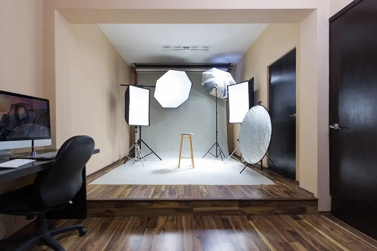 Profesjonalne studio fotograficzne z oświetleniem, stołkiem i komputerem.