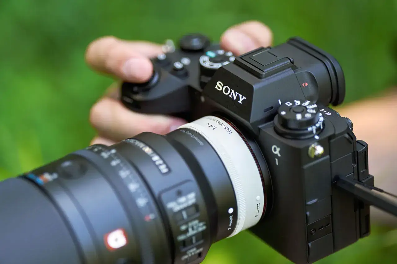 Dłoń trzyma aparat Sony Alfa z obiektywem makro. Idealny sprzęt do uchwycenia detali.