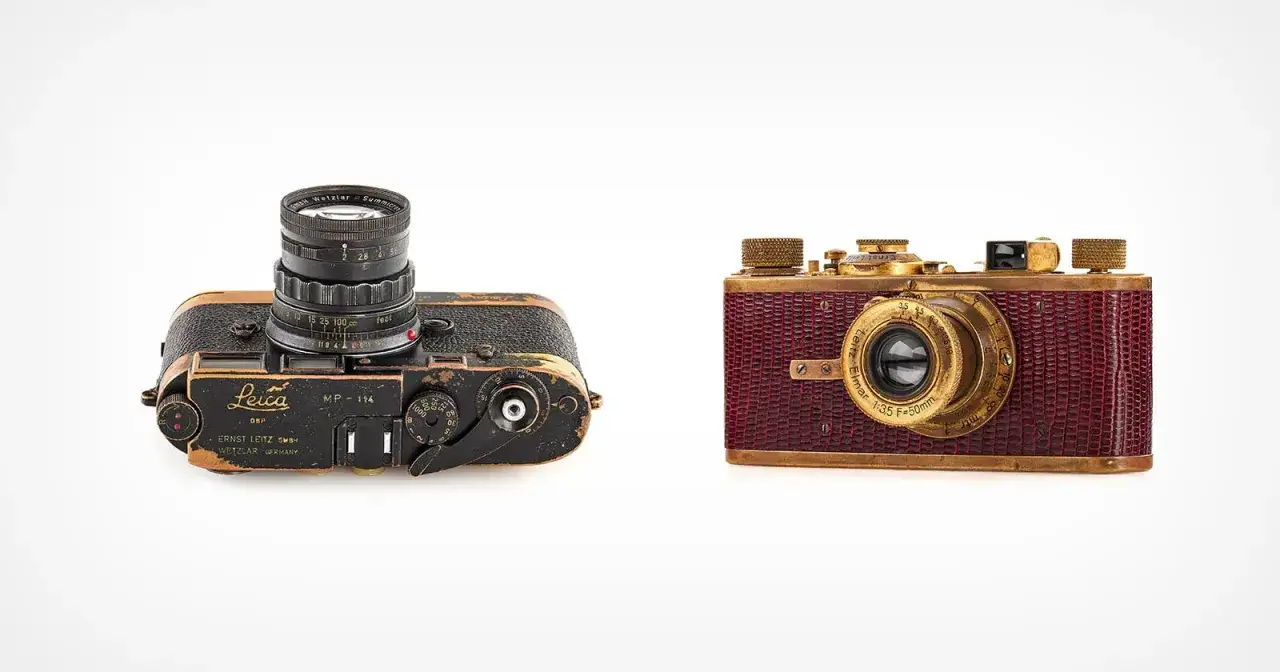 Dwa zabytkowe aparaty Leica, jeden czarny z obiektywem, drugi czerwony ze złotymi elementami. Prawdopodobnie najdroższy aparat fotograficzny na świecie.