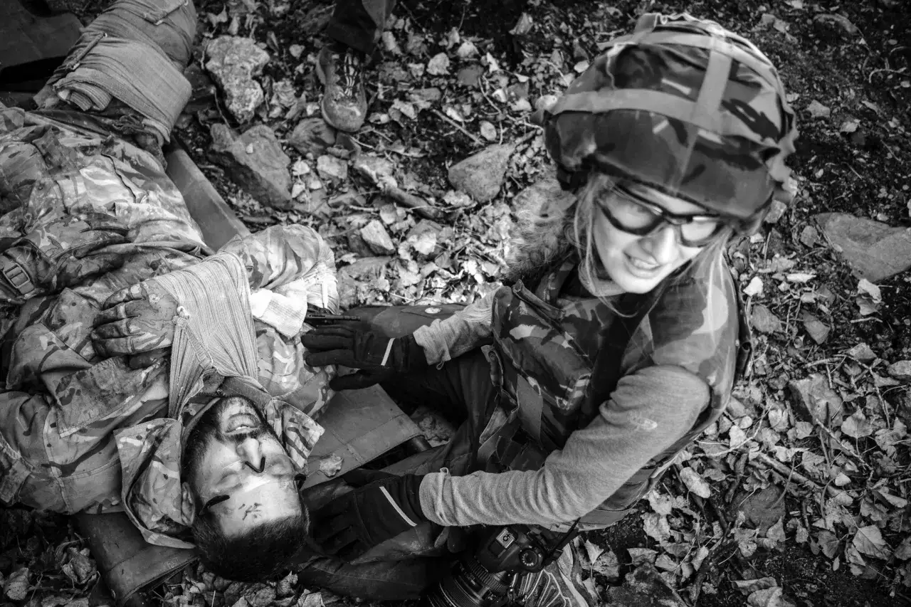 Wstrząsająca fotografia wojenna: ranny żołnierz opatrywany przez koleżankę, kt&oacute;ra trzyma aparat, by uwiecznić ten moment.