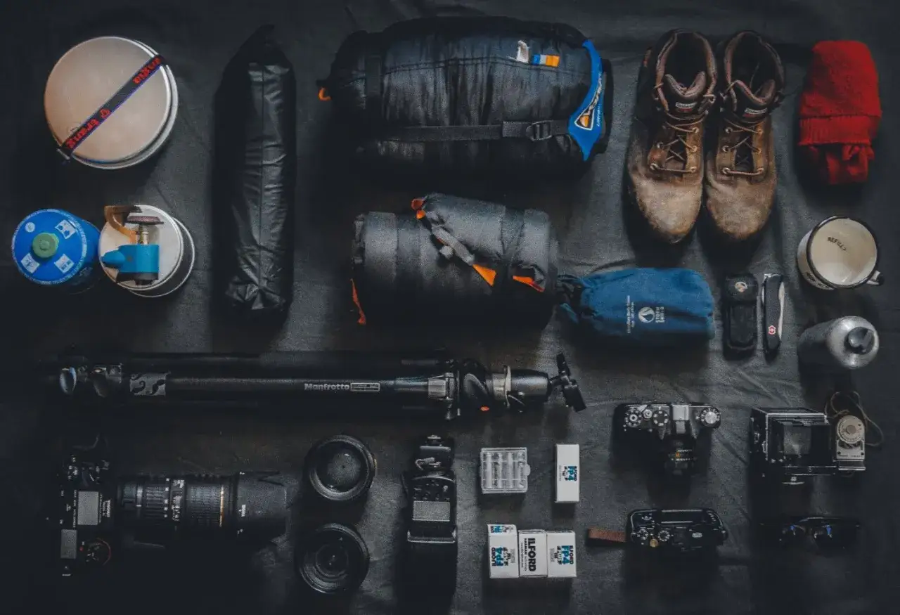 Sprzęt do fotografii podr&oacute;żniczej: śpiw&oacute;r, buty, aparat, obiektywy, statyw, kubek, termos, latarka, baterie, filmy.