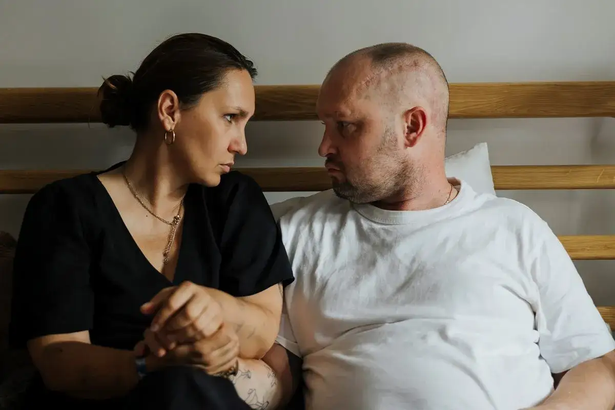 Anna Hernik i jej partner siedzą obok siebie, patrząc na siebie z powagą.